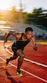 Focused Male Athlete Sprinting on Red Track at Sunset