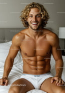 Smiling young man with curly hair sitting on bed