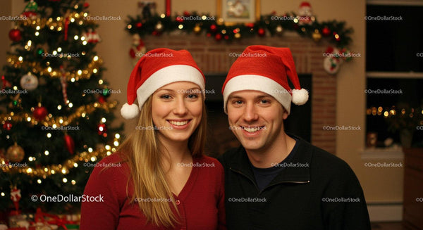 Smiling couple wearing Santa hats by Christmas tree