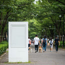 Empty white billboard in park with people walking dogs