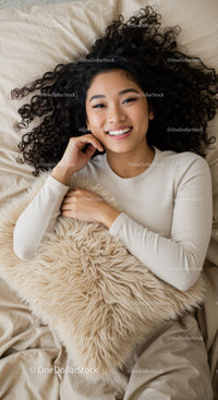 Happy young woman relaxing on cozy bed with fluffy pillow