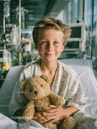 Young Boy Smiling in Hospital Bed Holding Teddy Bear