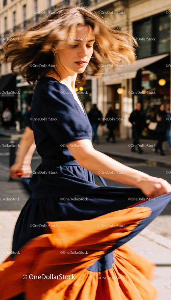 Woman twirling in flowing navy and orange dress on city street