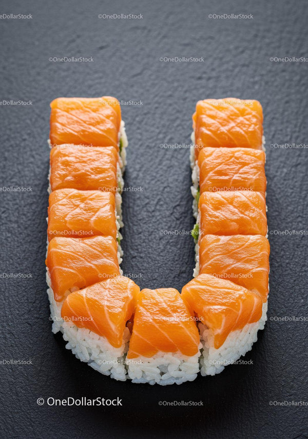 Fresh salmon sushi arranged in a U shape on slate