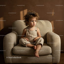Thoughtful toddler sitting on beige textured armchair