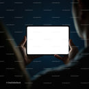 Person Holding Tablet with Bright Screen in Dark Room
