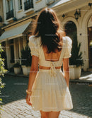Stylish Woman in Cream Summer Dress Walking in Sunlit Street