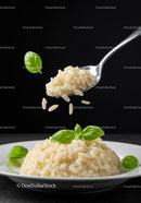 Creamy risotto with fresh basil leaves on white plate
