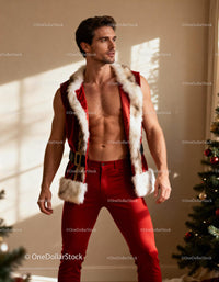 Fit man in festive red holiday vest near Christmas tree