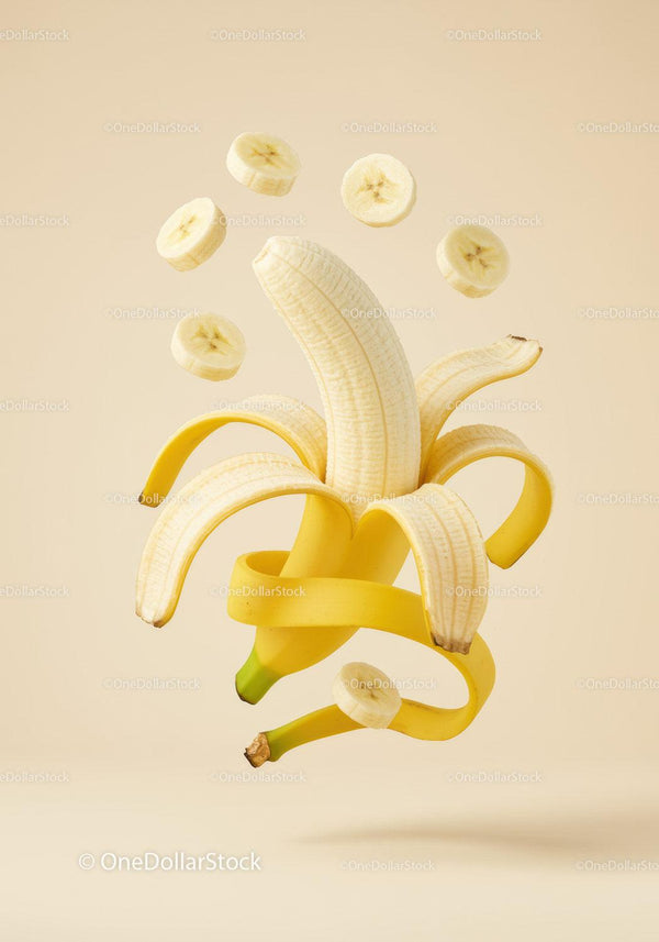 Peeled banana with floating banana slices on beige background
