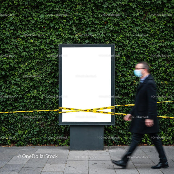 Masked man walking past blank urban billboard with caution tape JPG Mockup Image