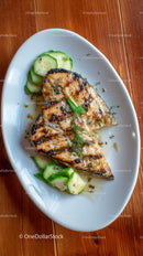 Grilled Fish with Fresh Cucumber Slices and Herbs on White Plate