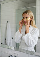 Woman Applying Gold Eye Patches During Skincare Routine