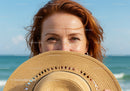 Smiling Woman with Sunhat at Beach During Sunny Day