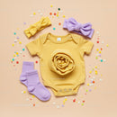 Yellow Baby Onesie with Lilac Accessories and Confetti