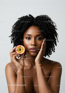 Portrait of an African American Woman with Curly Hair Holding Passion Fruit