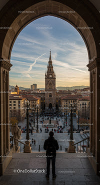 View of a Gothic Style Cathedral Tower in a Busy City Square at Sunset