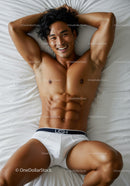 Fit young man relaxing on white bed smiling