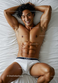 Fit young man relaxing on white bed smiling