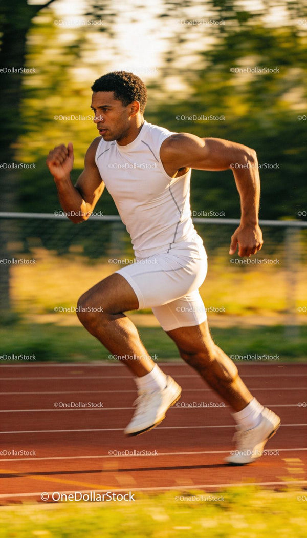 Focused male sprinter accelerating on the track outdoors