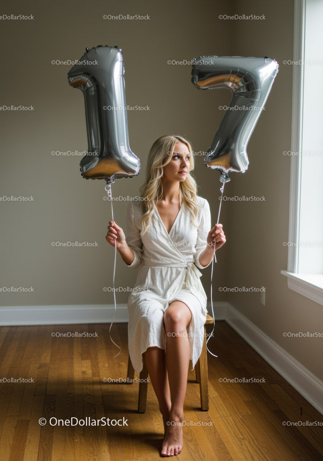 Young woman celebrating 17th birthday with silver balloons