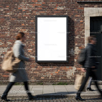 Pedestrians walking past blank poster on brick wall