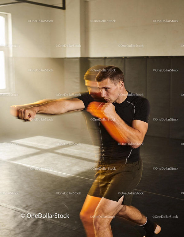Focused young man practicing boxing punches indoors