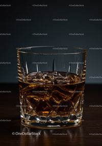 Amber whiskey in crystal glass with ice cubes on dark background