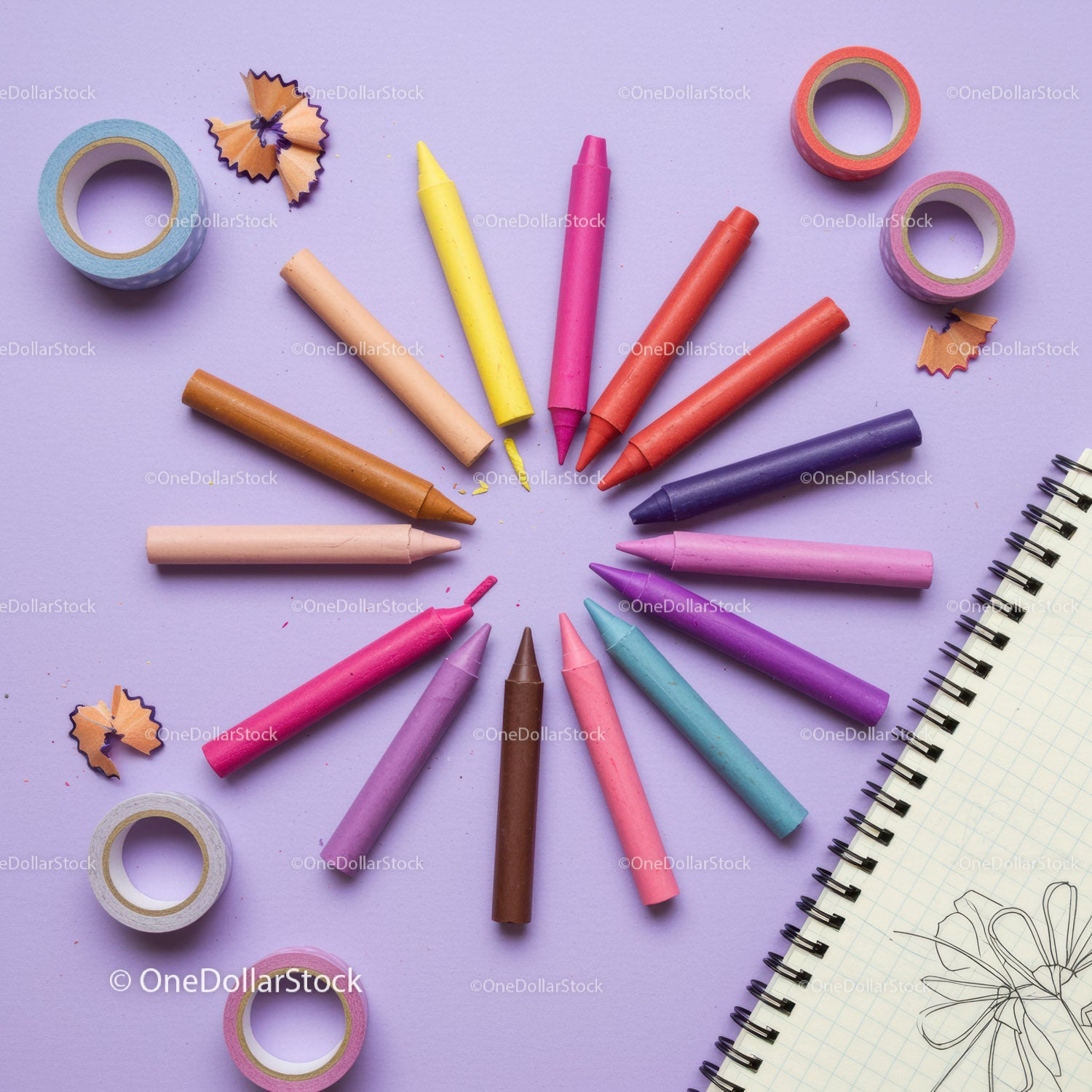 Colorful crayons arranged in a circle with notebook sketch
