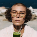 Confident Young Woman Wearing Sunglasses with Green Juice in City Scene