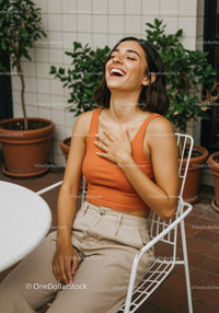 Joyful Woman Laughing Outdoors with Greenery and Urban Terrace