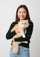 Young woman holding fluffy ginger cat indoors