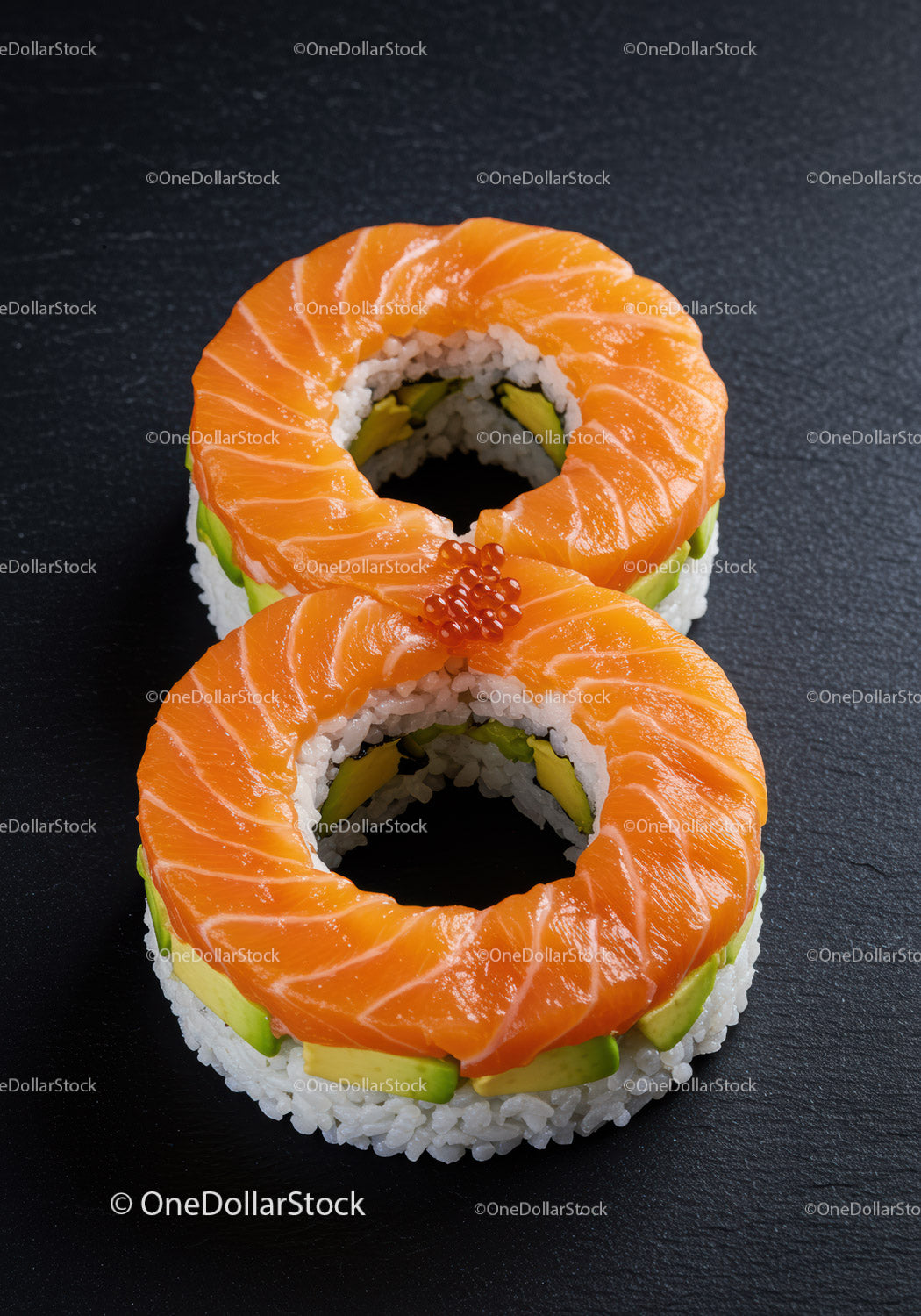 Dwie okrągłe rolki sushi z łososiem i awokado na czarnym tle