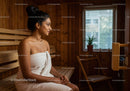 Relaxing Woman Sitting in Sauna Room with Wooden Interior and Natural Light