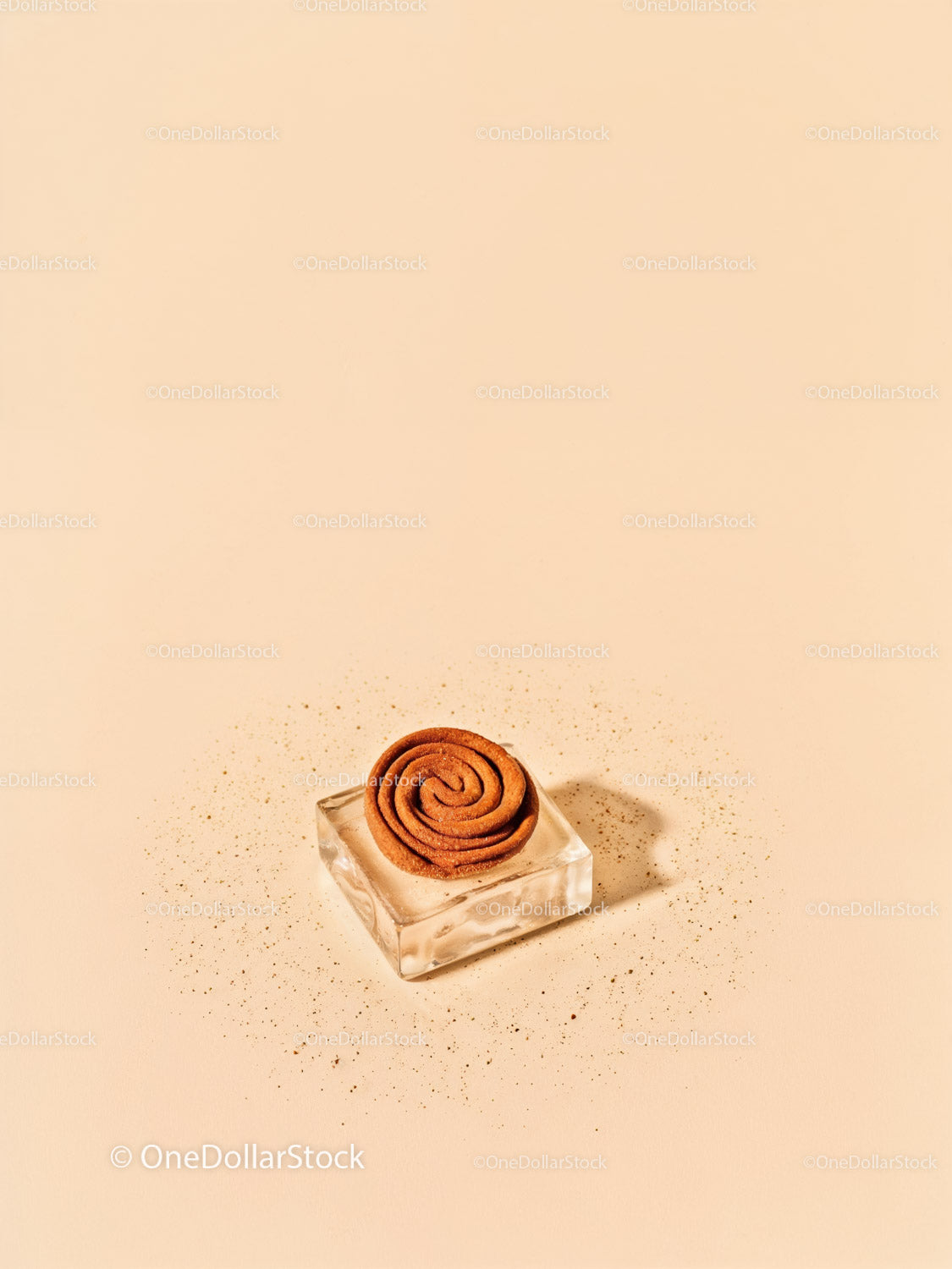 Minimalist cinnamon coil on glass block with spice dust
