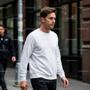 Man in White Sweatshirt Walking Calmly on City Street
