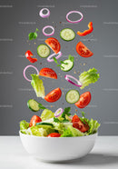 Fresh vegetable salad ingredients falling into bowl