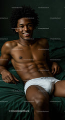 Smiling young man relaxing on dark green bed linen