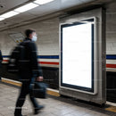 Commuter walking past blank digital billboard in subway station