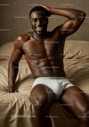 Smiling muscular man relaxing on beige bed in white briefs