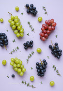 Fresh green red and black grapes with thyme herbs on pastel