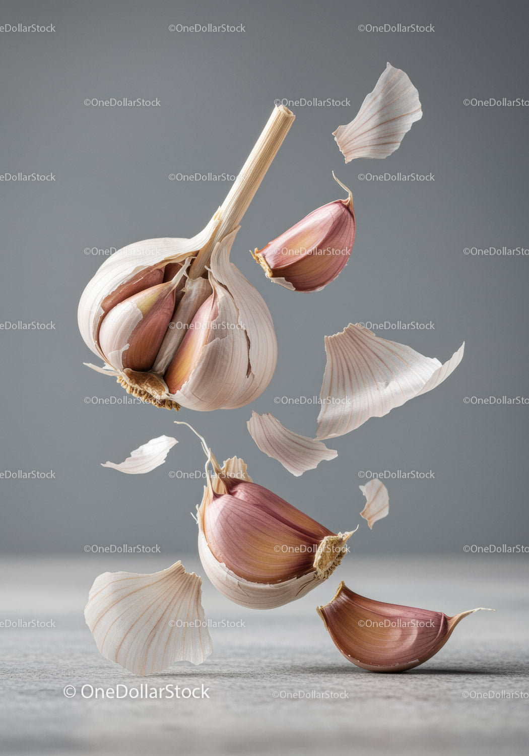 Floating garlic cloves and translucent skins on gray background