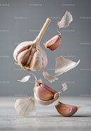 Floating garlic cloves and translucent skins on gray background