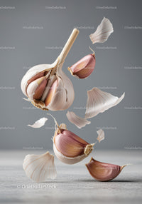 Floating garlic cloves and translucent skins on gray background