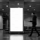 Blurred man walking by empty billboard in modern lobby
