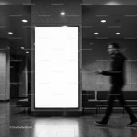 Blurred man walking by empty billboard in modern lobby