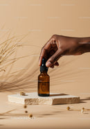 Elegant Brown Glass Dropper Bottle in Hand on Neutral Background