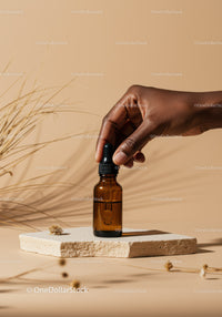 Elegant Brown Glass Dropper Bottle in Hand on Neutral Background