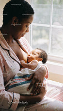 Mother lovingly breastfeeding her newborn baby at home