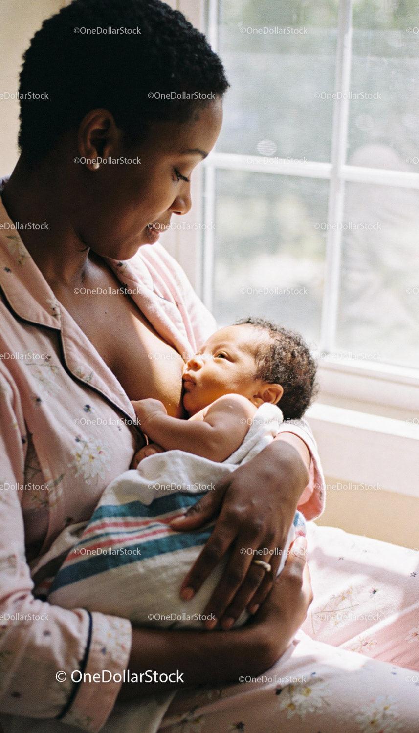 Mother lovingly breastfeeding her newborn baby at home